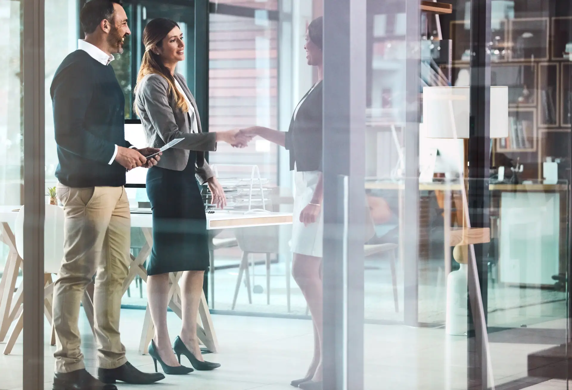 Woman shaking hands with two people in a conference room