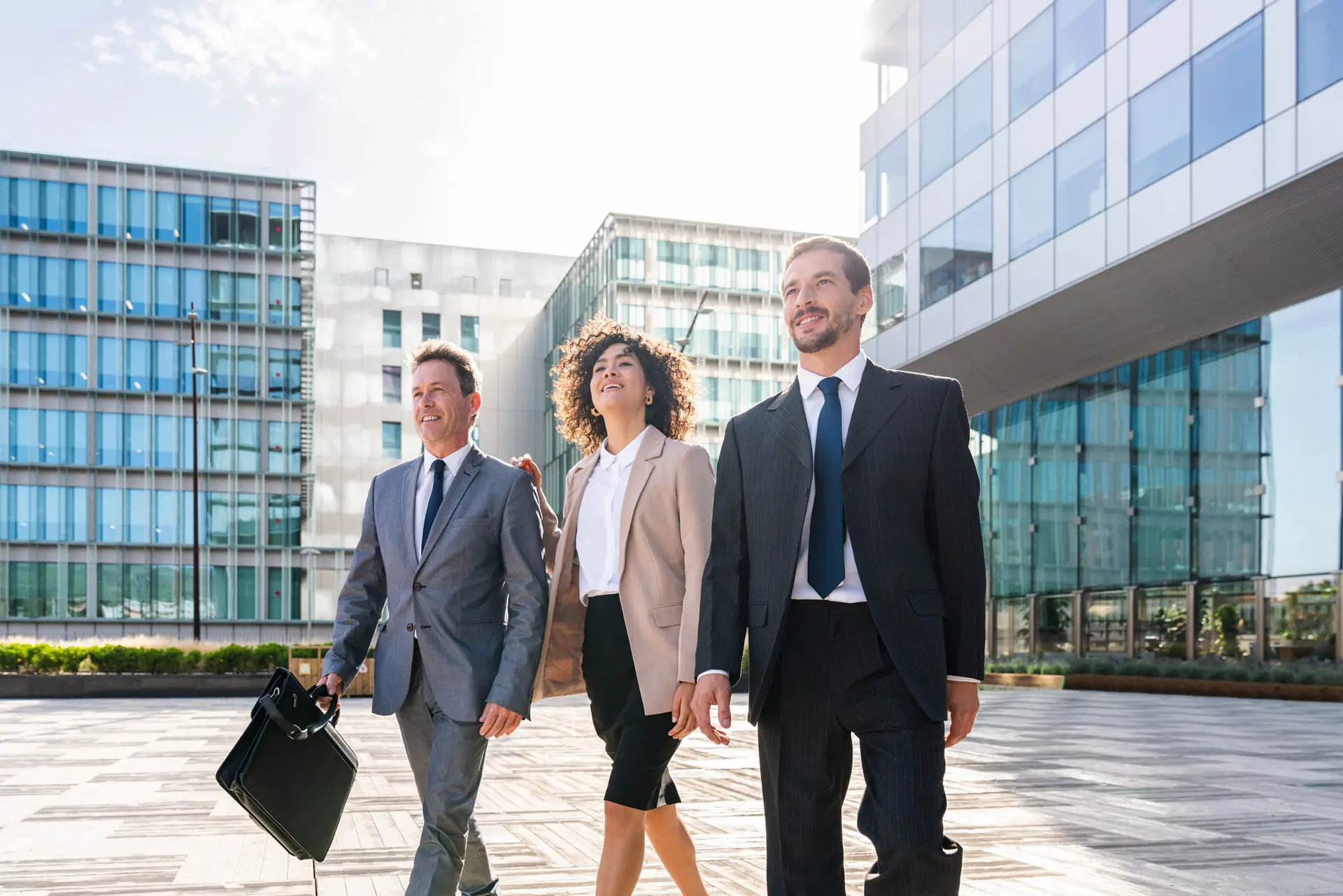 Three business people walking out of a commercial building