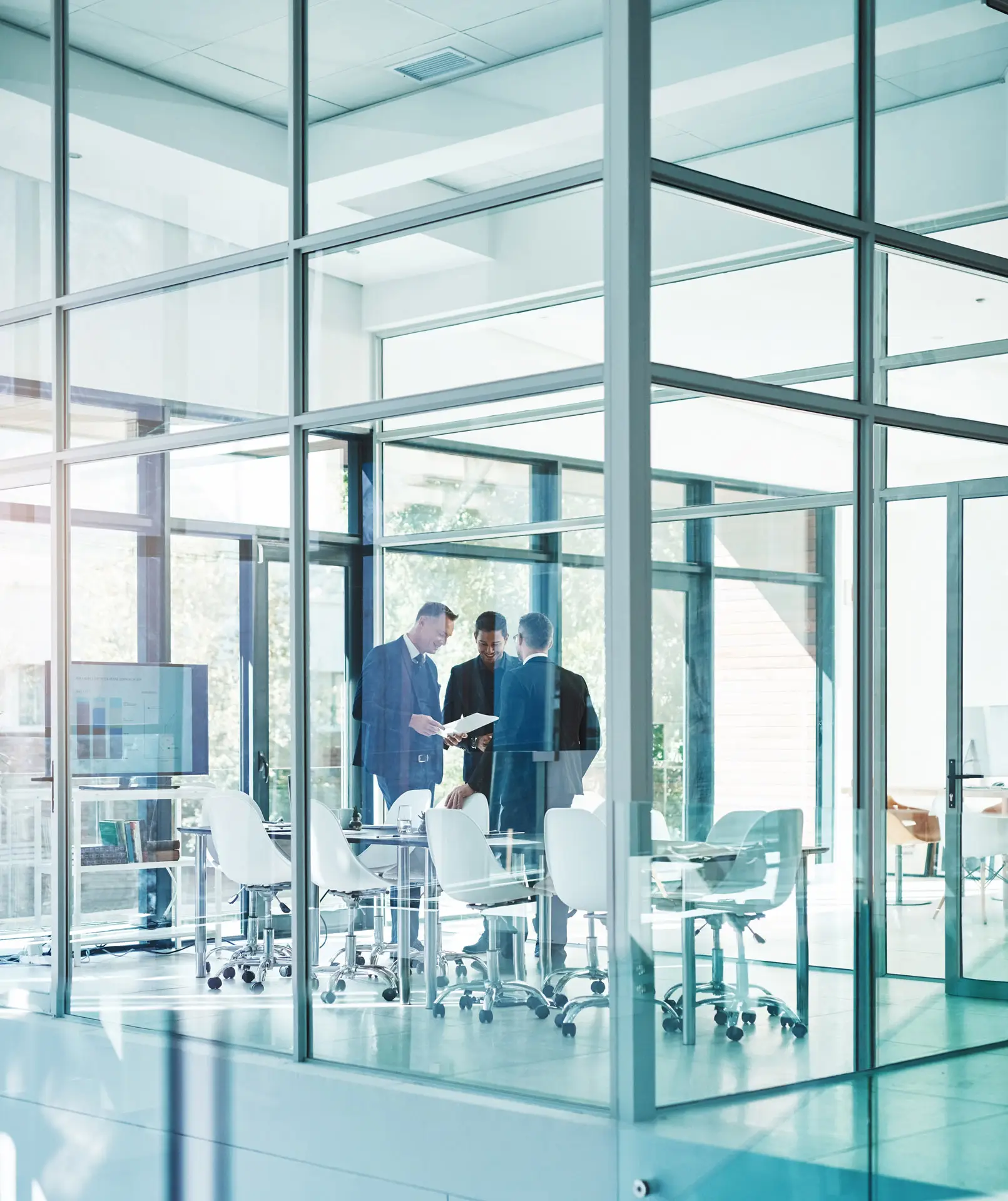 Three businessmen meeting in a glass conference room
