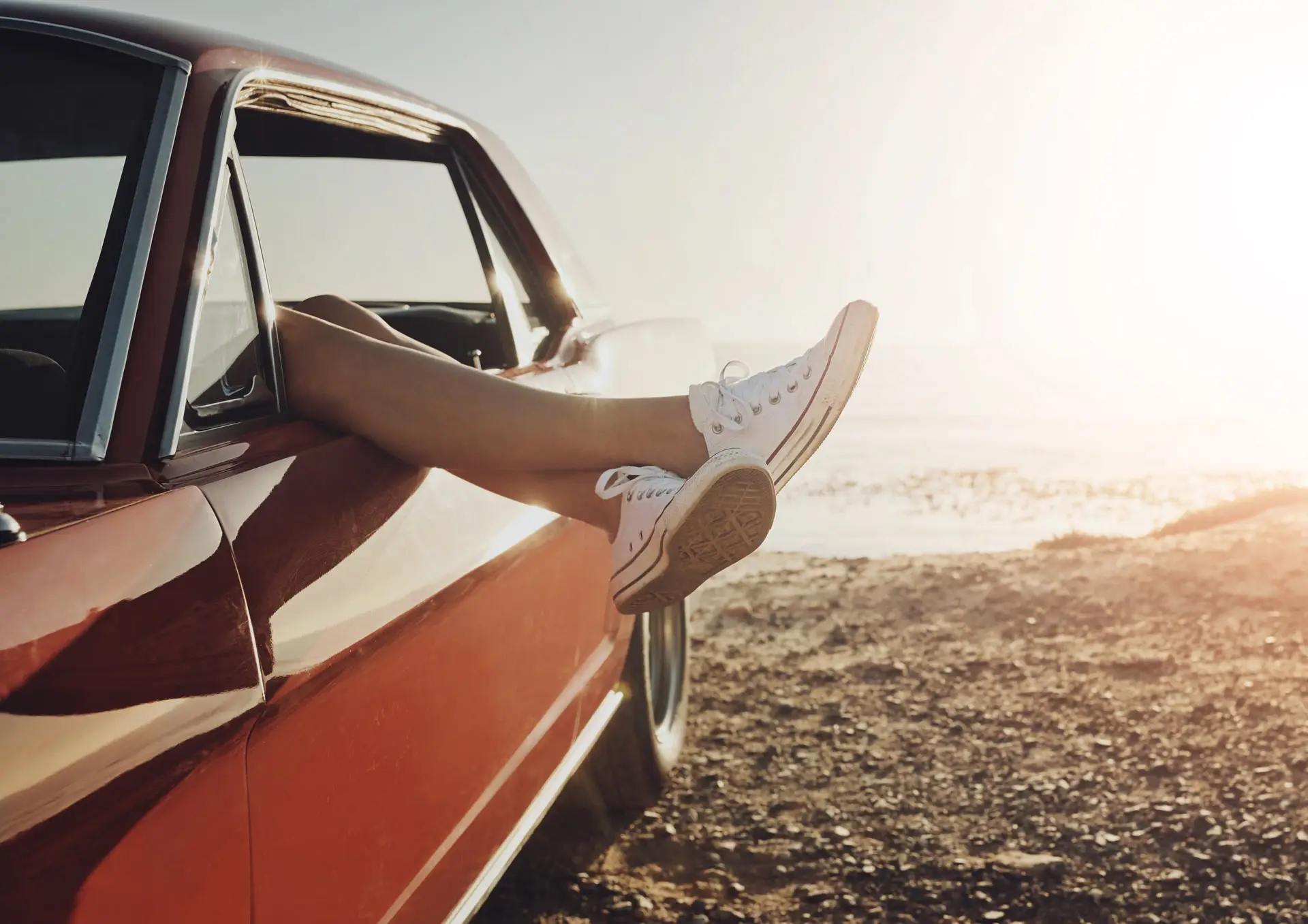 Person with legs causally lounging out of car door on the beach