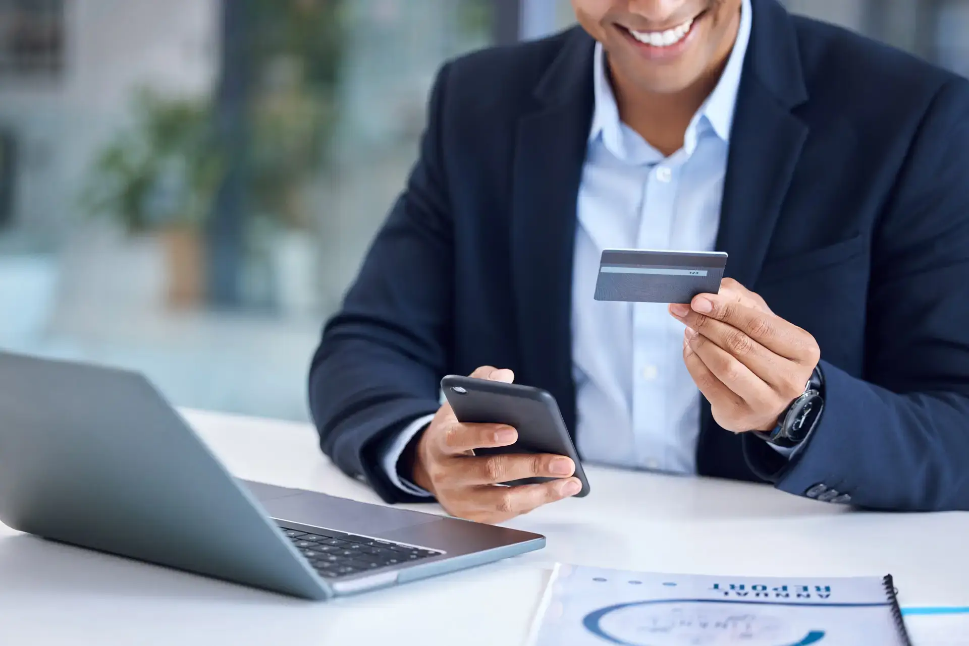 Man holding a phone and a credit card while smiling down at them