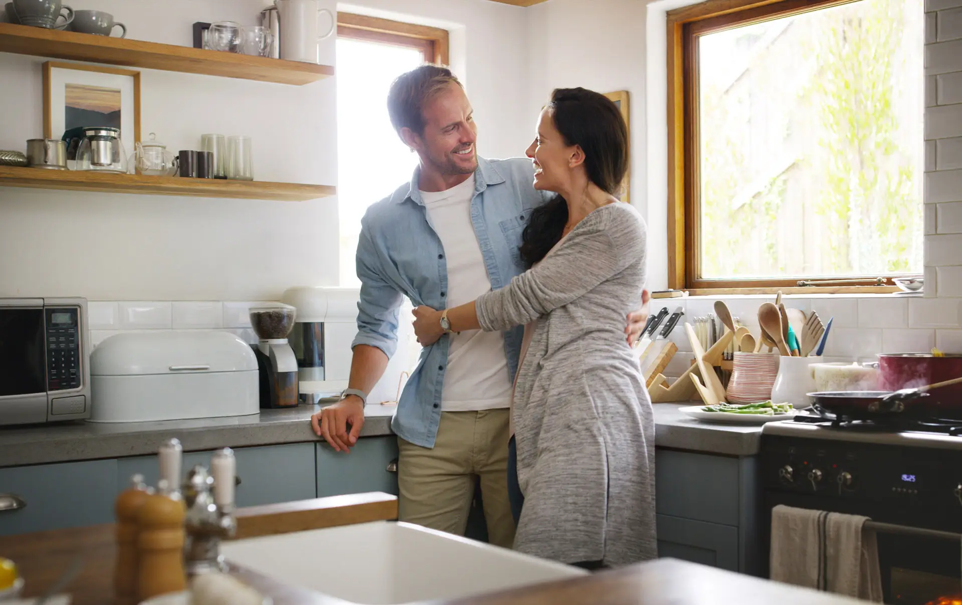 Couple embracing and smiling at each other in their house's kitchen