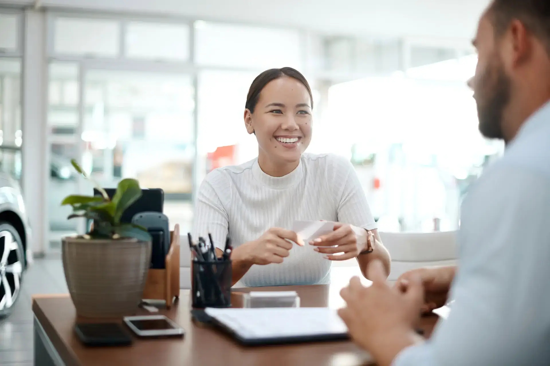 Woman sitting at a desk with a car sales person
