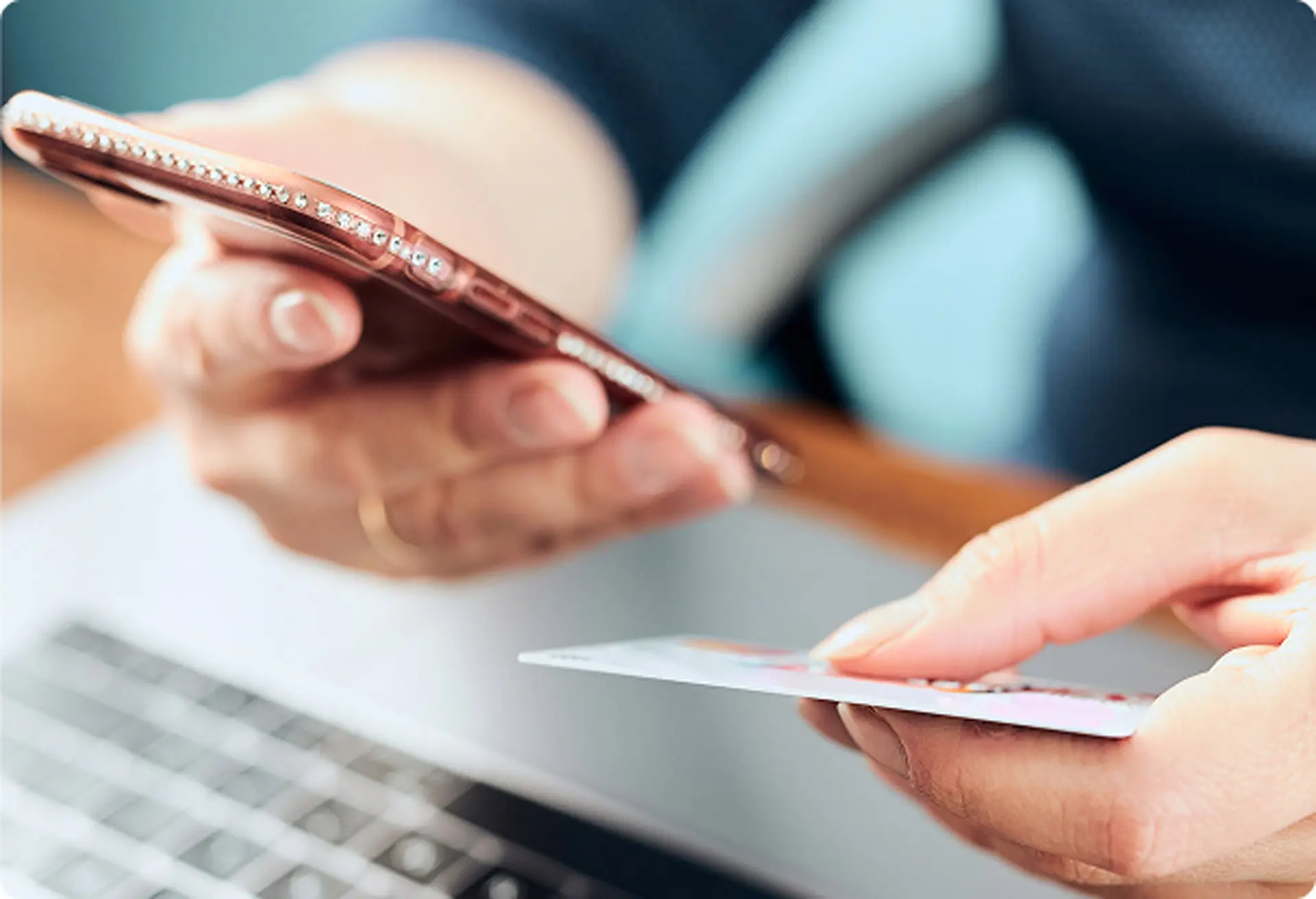 Closeup of hands holding a credit card while looking at a phone