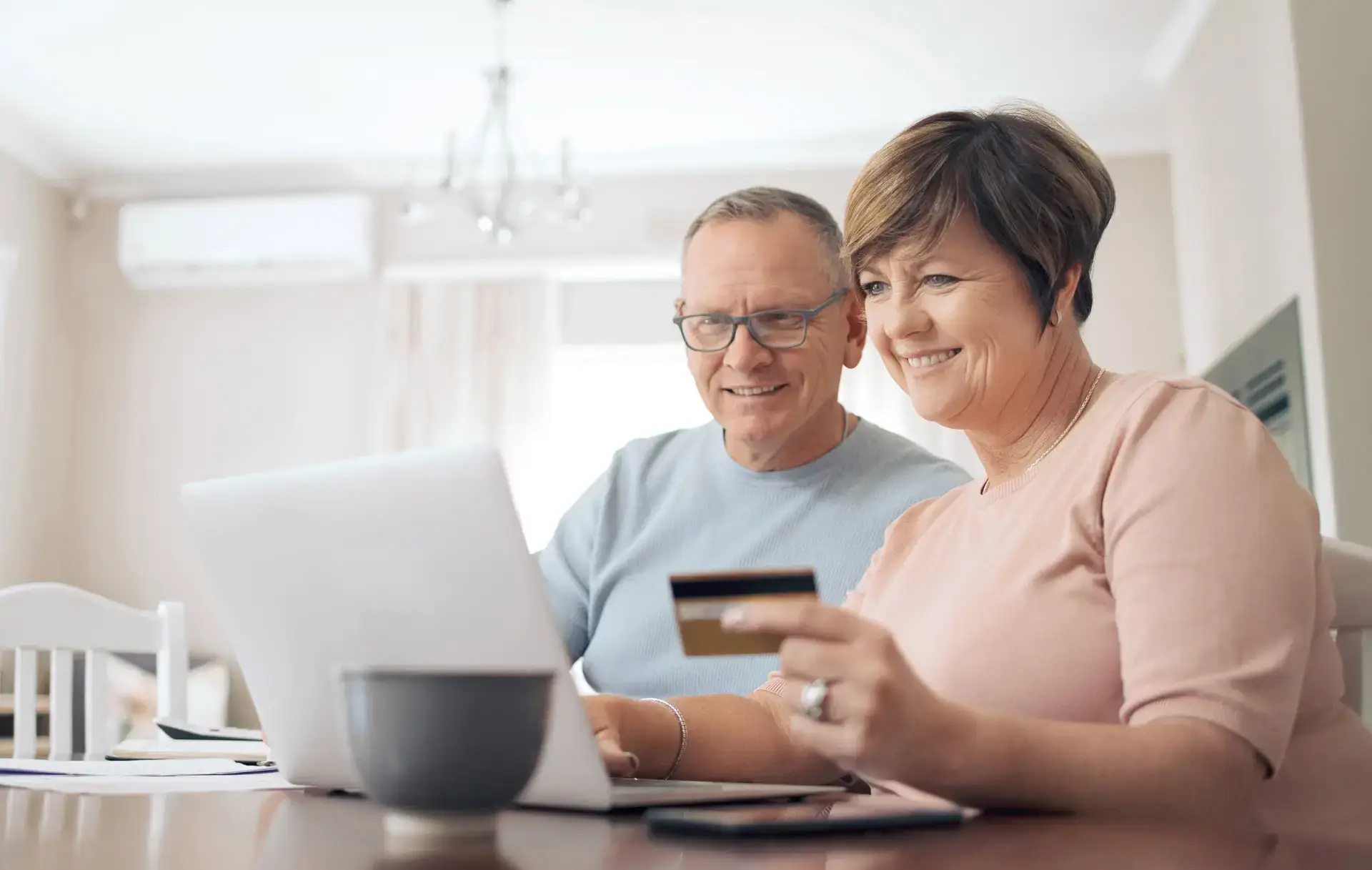 Couple using their laptop together with the woman holding a credit card