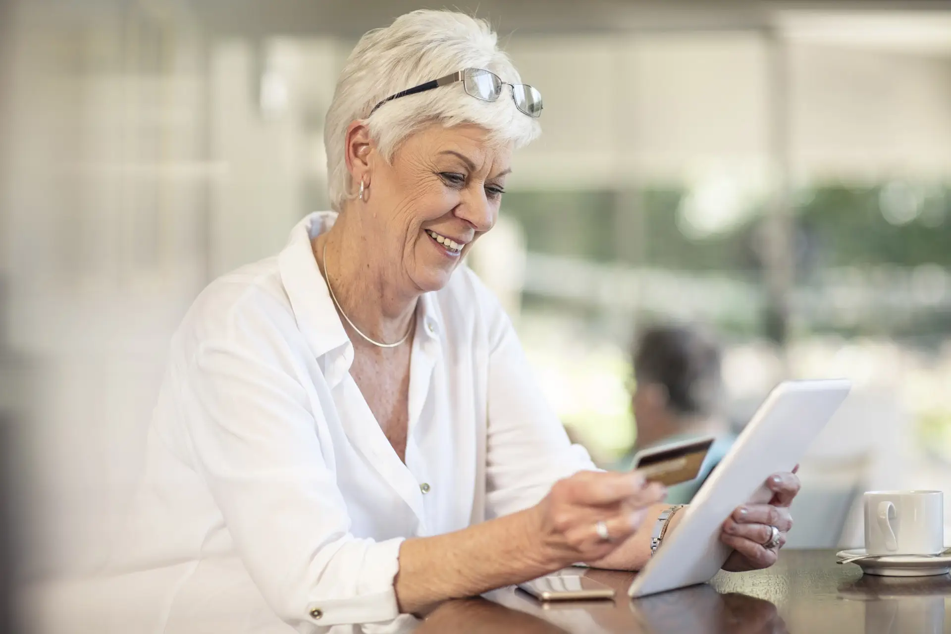 Senior woman holding a credit card while looking at her phone and smiling