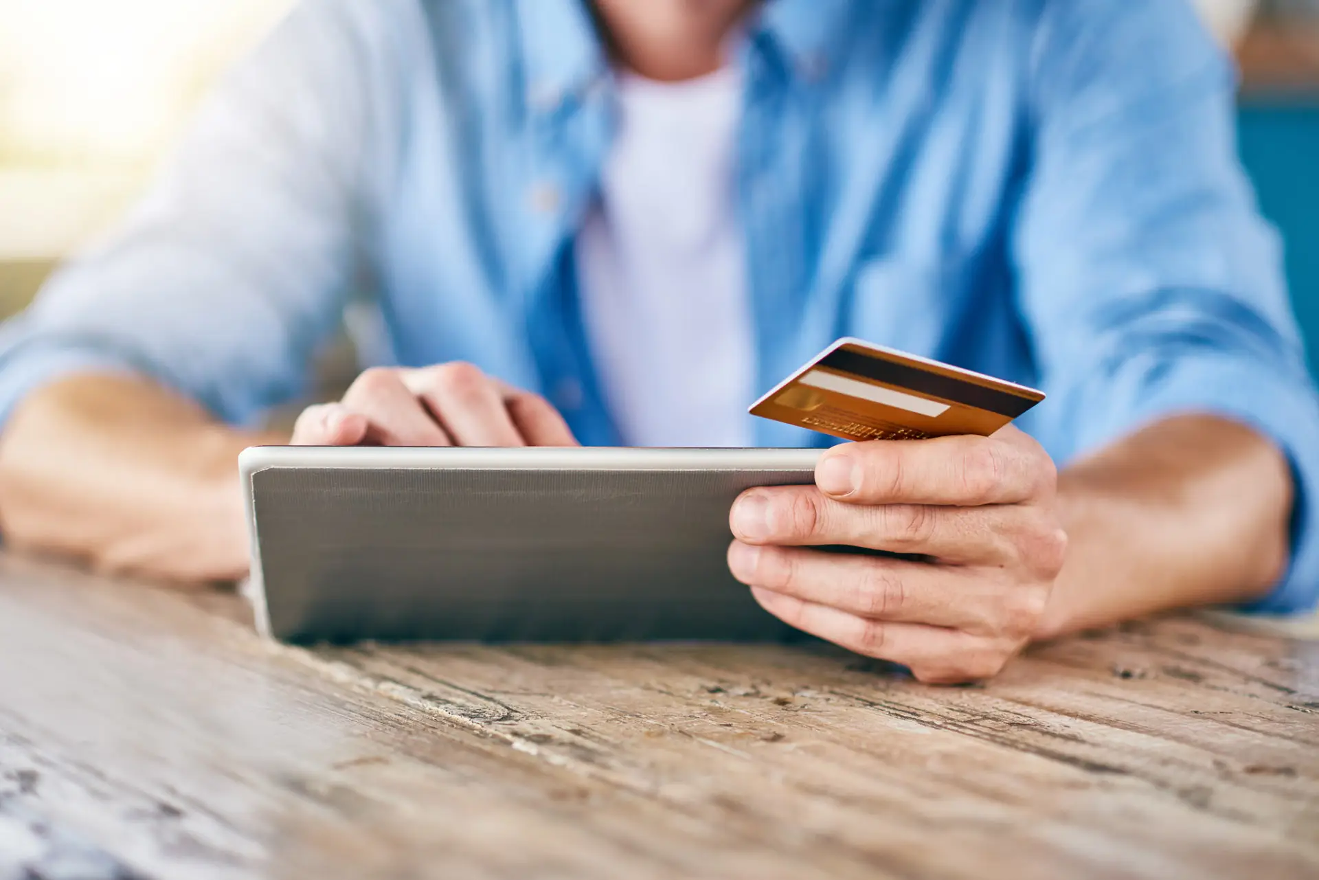 Closeup of someone using a tablet while holding a credit card