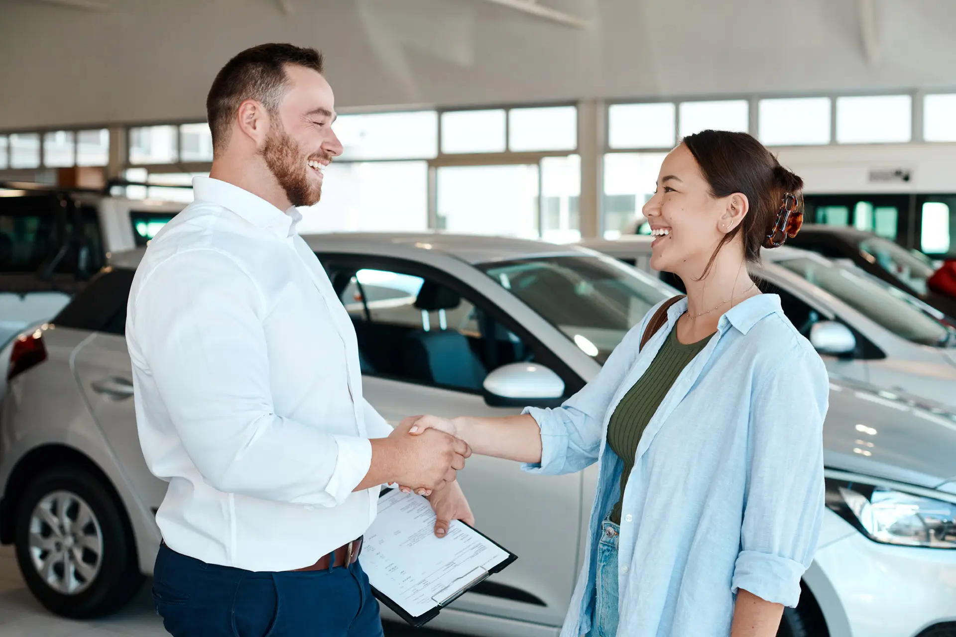 Woman shaking a car salesman's hand in front of the car