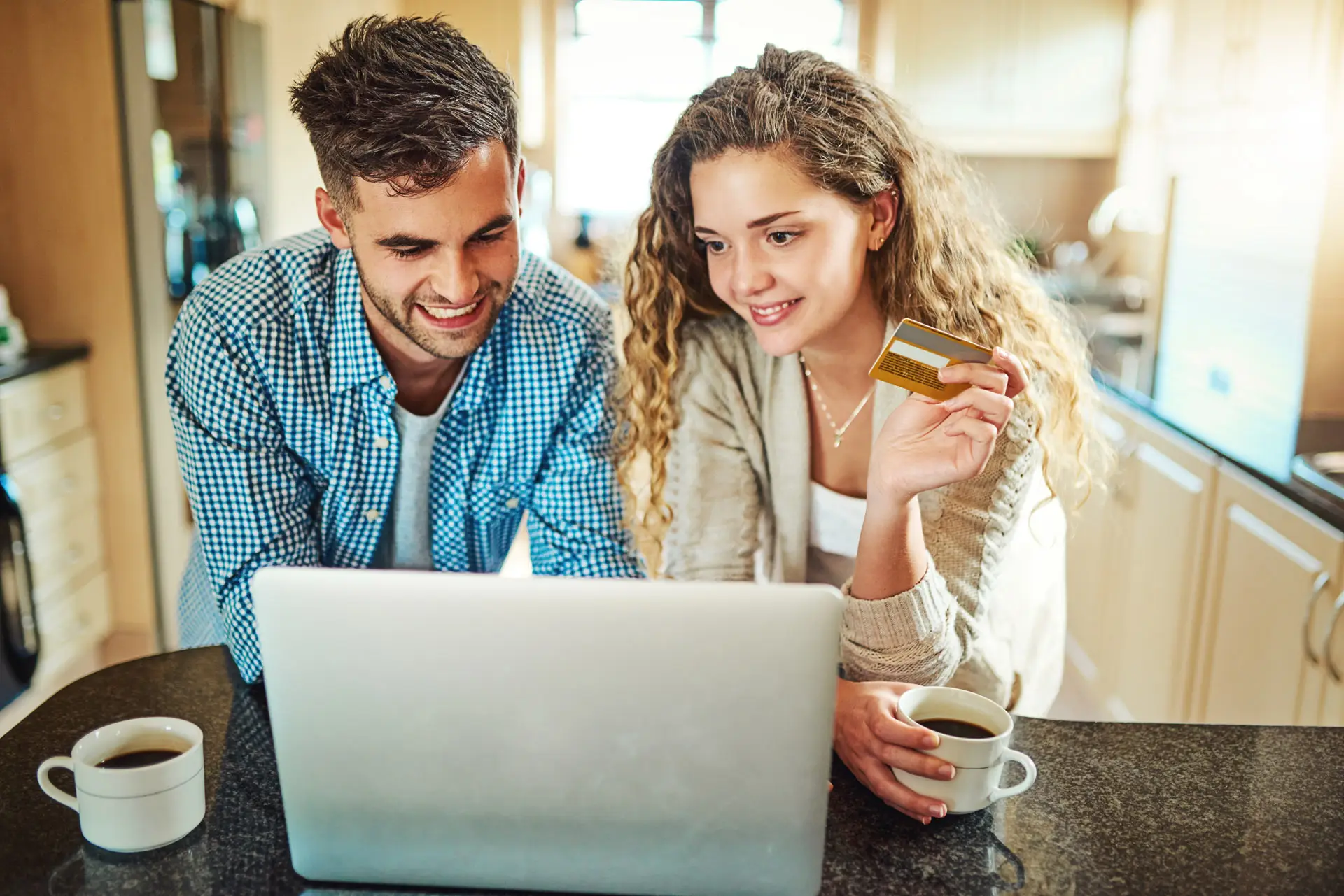 Young couple using a laptop while holding a credit card